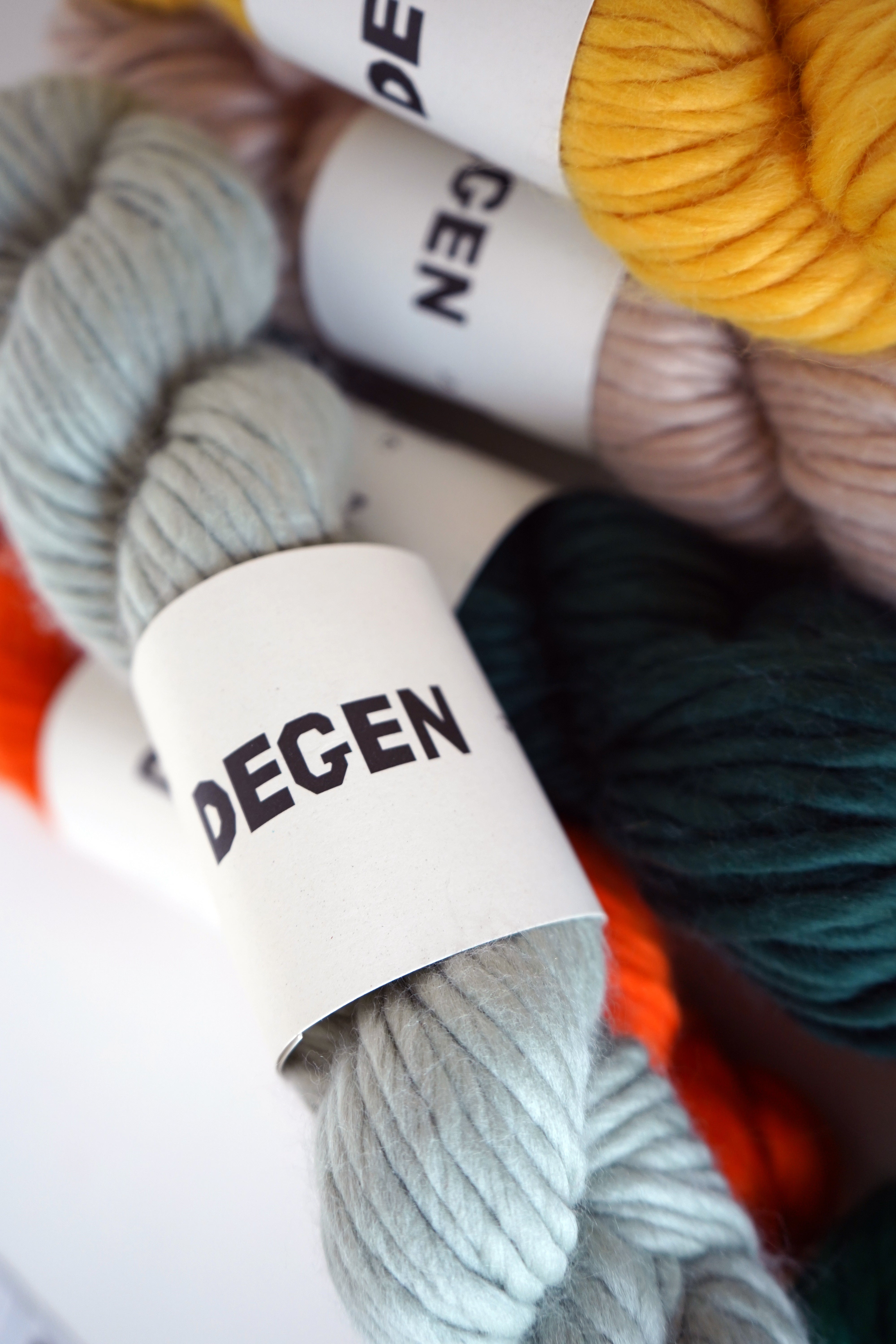 Colorful yarn skeins with 'DEGEN' labels on a white background