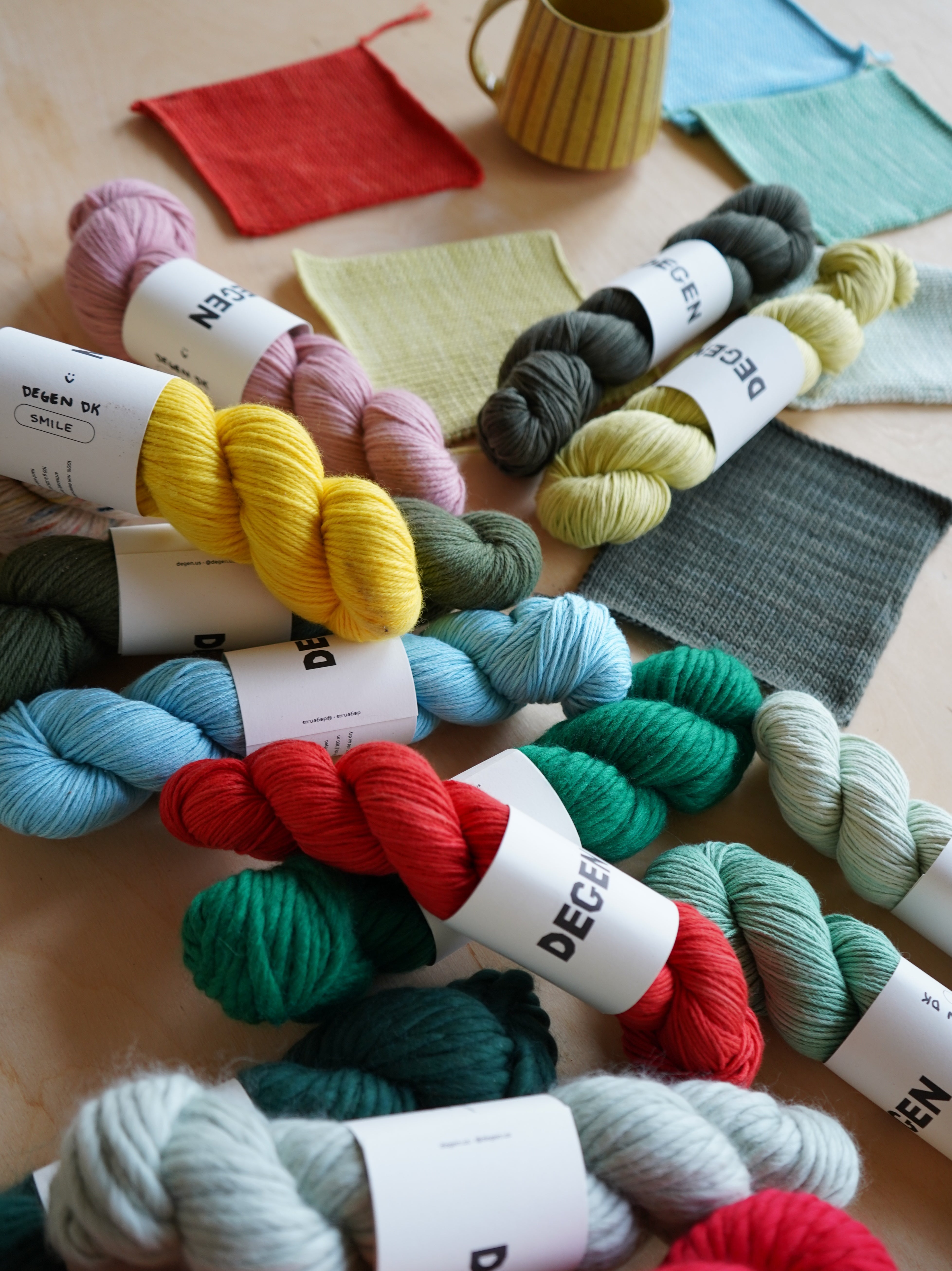 Colorful yarn skeins with DEGEN labels on a wooden surface